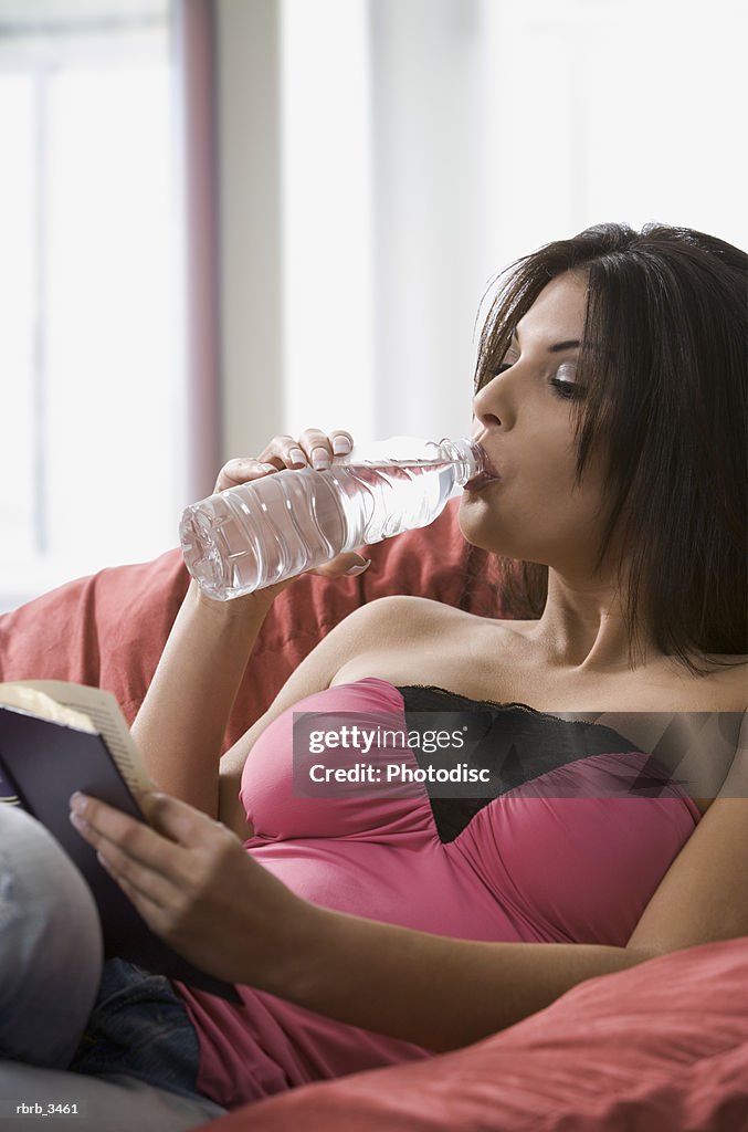 Young woman drinking water and reading a book