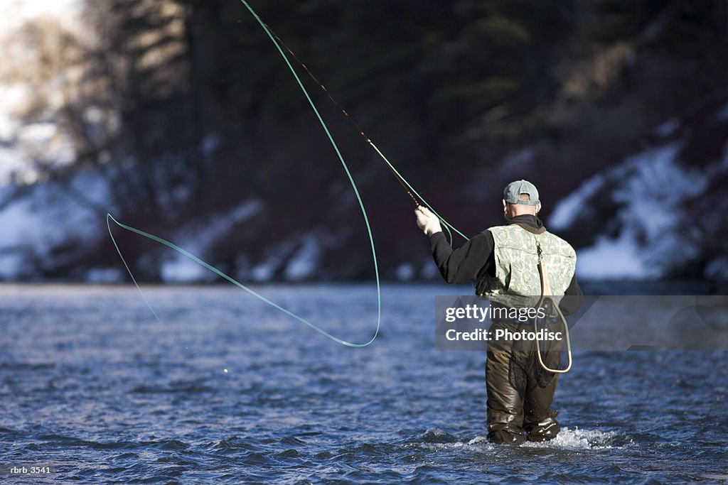 Rear view of a mature man fly-fishing in a river