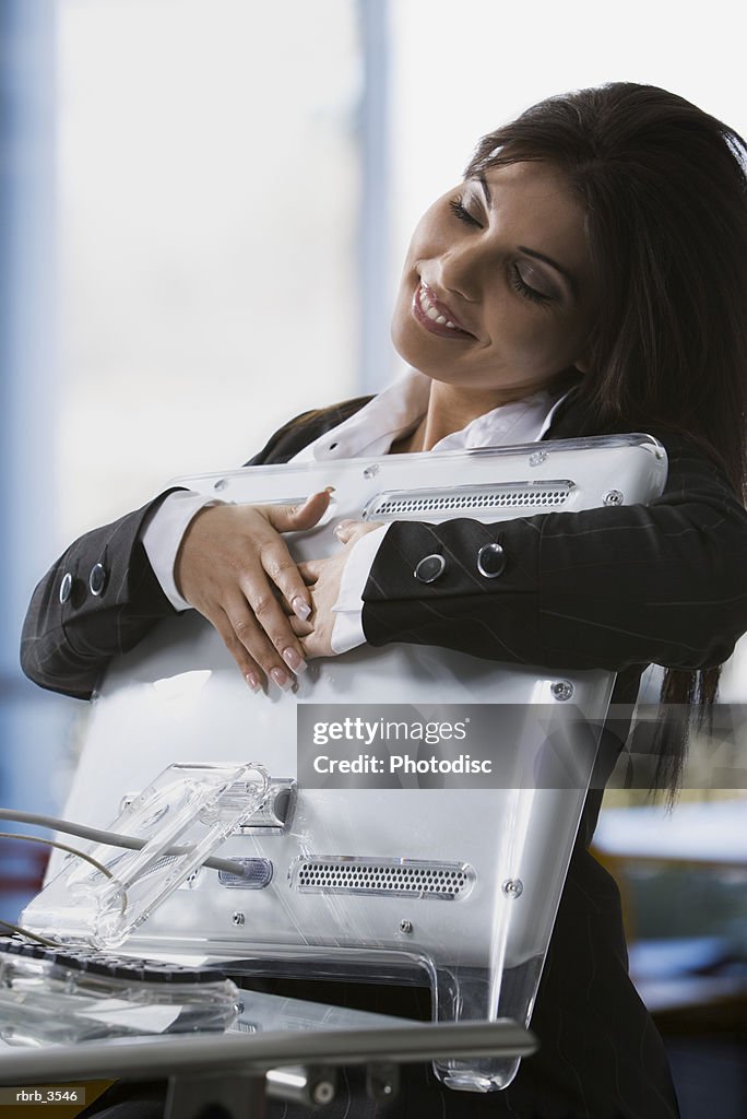 Young woman holding a computer monitor with her eyes closed