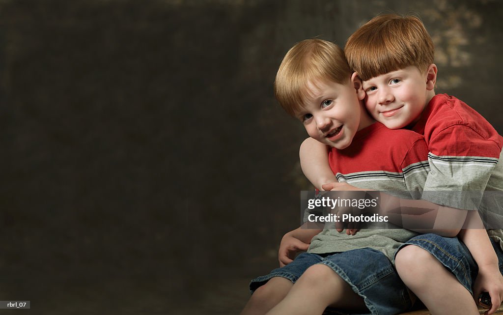 Two redheaded brothers dressed in shorts and red and grey shirts hug each other