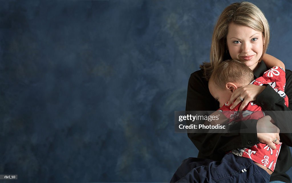 A caucasian blonde mother holds her young son and gives him a loving hug