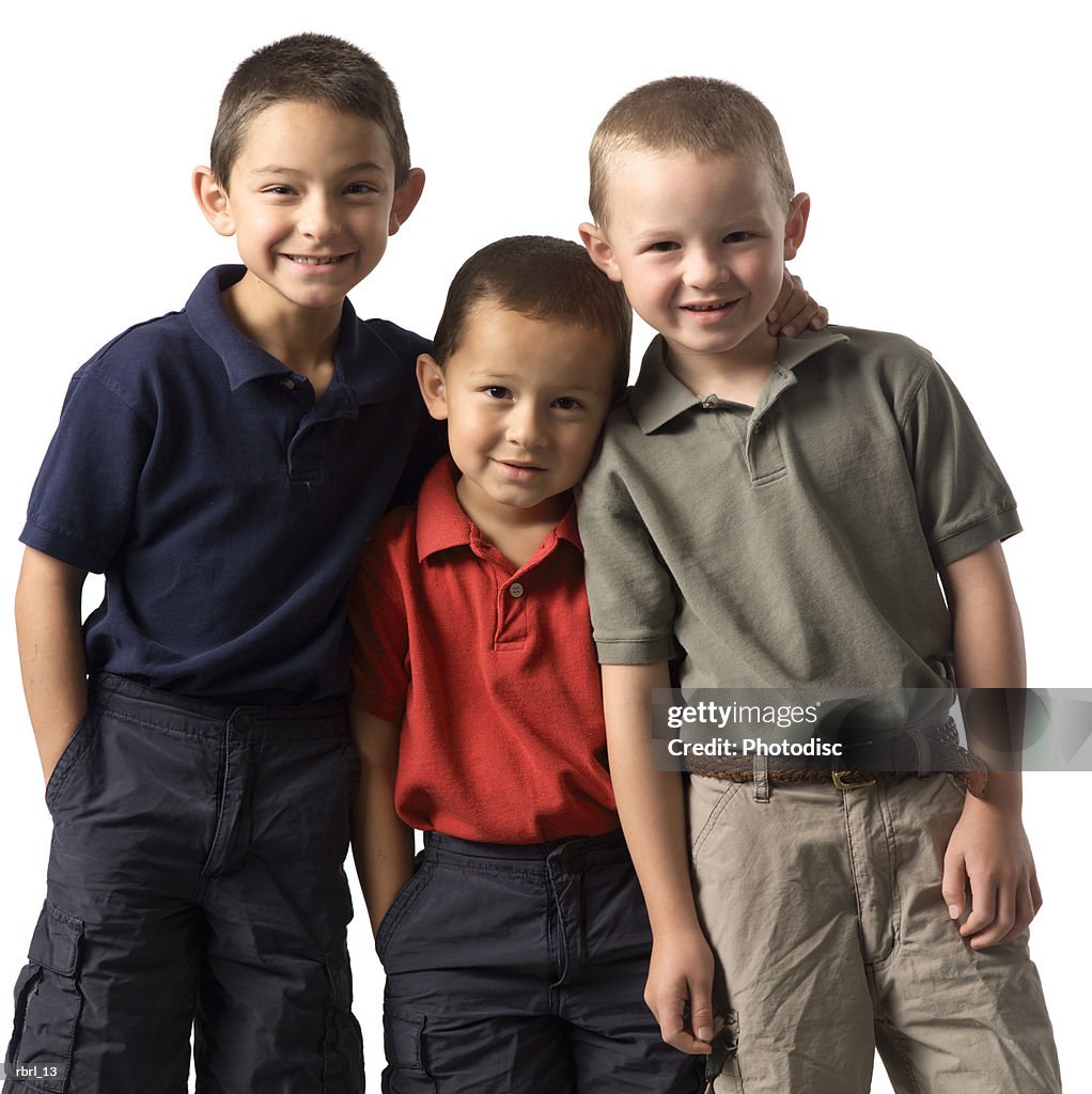 A group of three caucasian child brothers put their arms around each other and smile at the camera