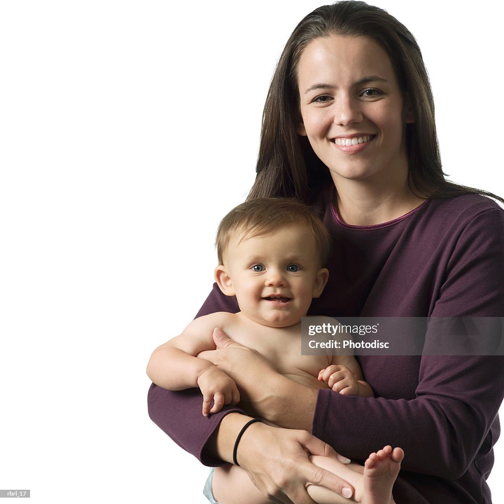 A young caucasian mother smiles as she holds her baby on her lap