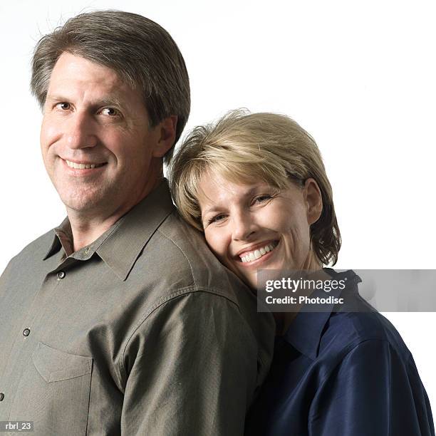 an adult caucasian couple smile as the woman rests her head on her husbands shoulder and smiles - smile stock-fotos und bilder