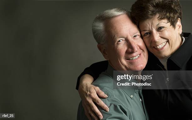 an elderly caucasian couple smile brightly as they hug each other - smile stock-fotos und bilder