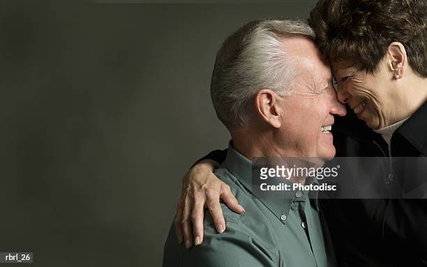 an elderly caucasian couple lovingly look into each others eyes - senior woman studio stock-fotos und bilder
