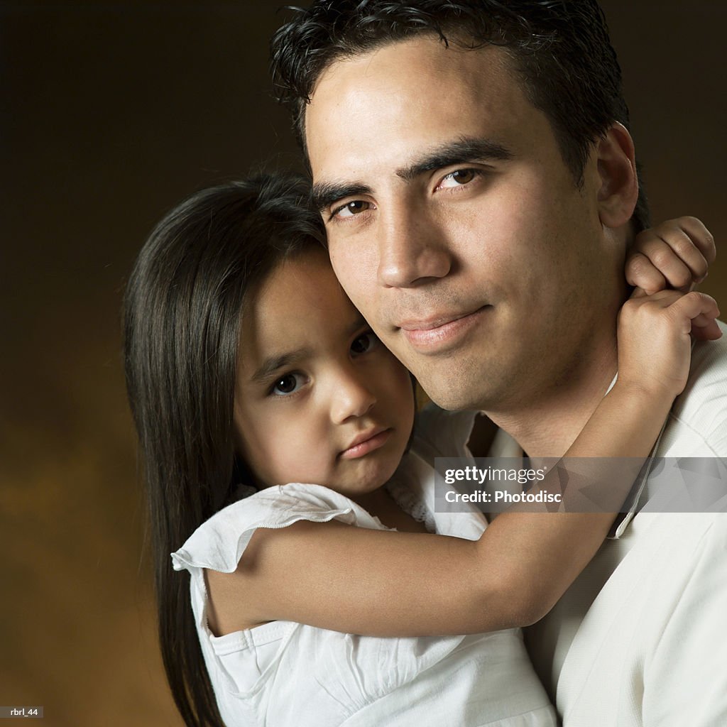 A young ethnic father loving recieves a hug from his little daughter