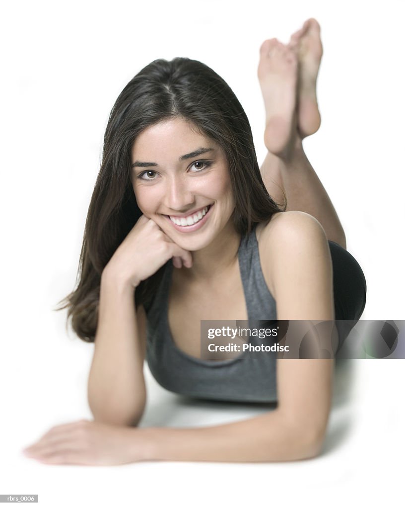 Full body shot of a young adult woman in a workout outfit as she lays down and smiles