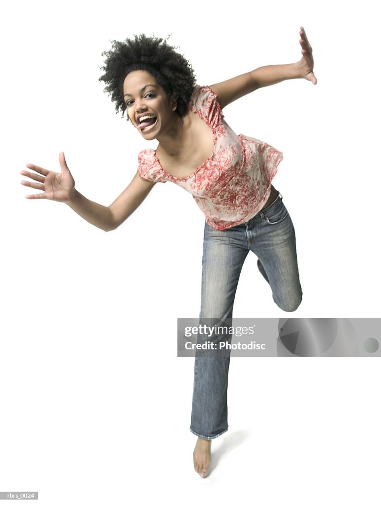 Low angle full body shot of a young adult woman as she playfully jumps around