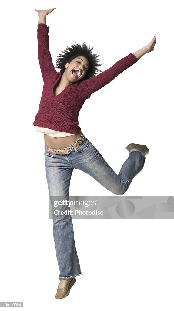 Full body shot of a young adult woman as she playfully jumps and throws up her arms