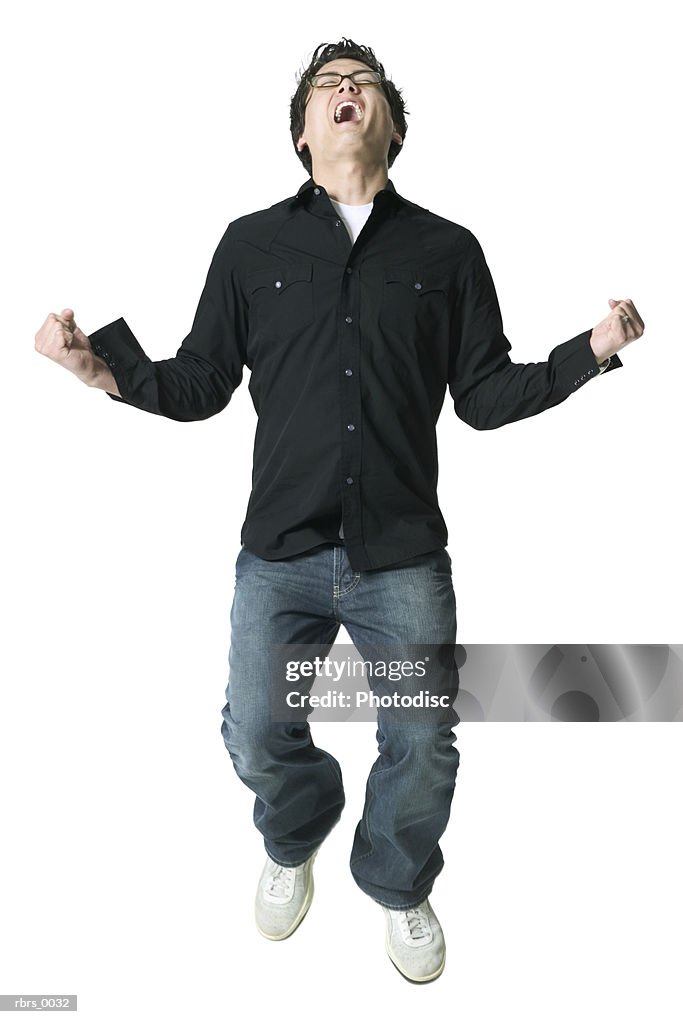 Full body shot of a young adult man in a black shirt as he jumps and throws back his head