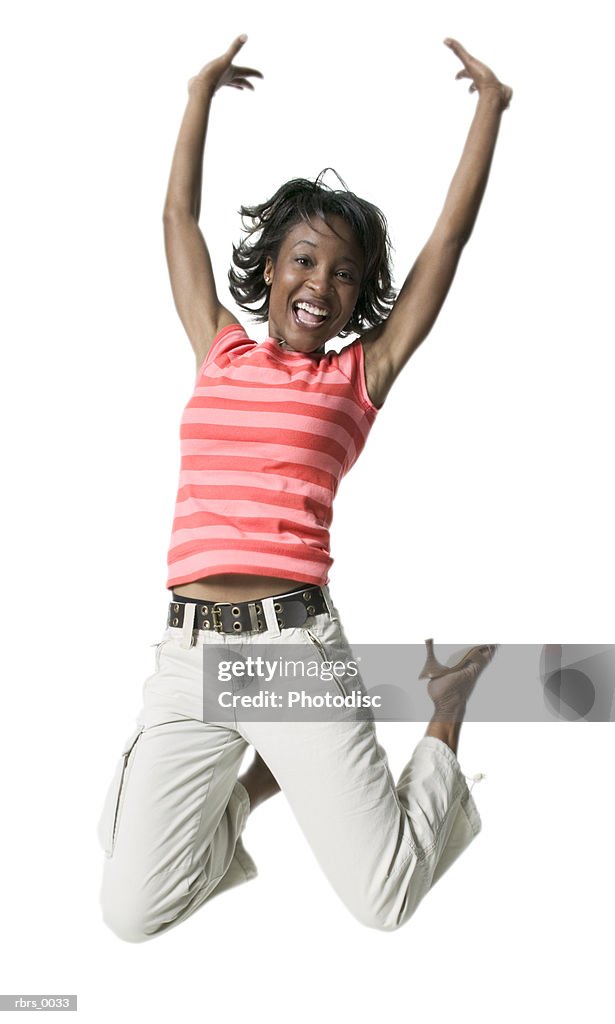 Full body shot of a young adult female in a striped shirt as she jumps into the air
