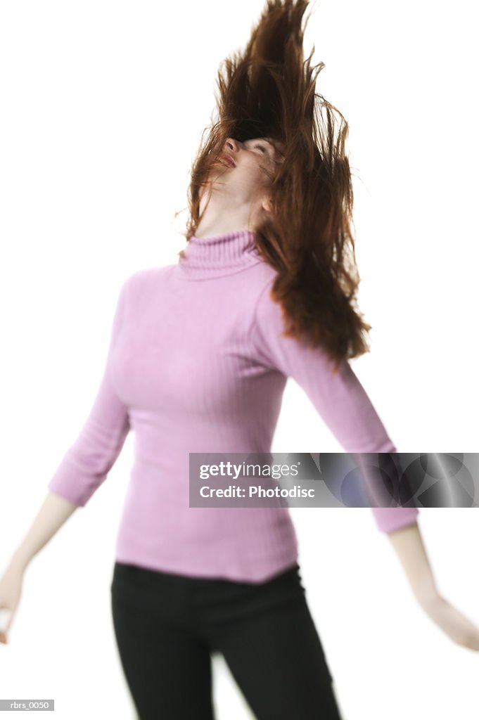Medium shot of a teenage female in a pink sweater as she playfully tosses her hair around