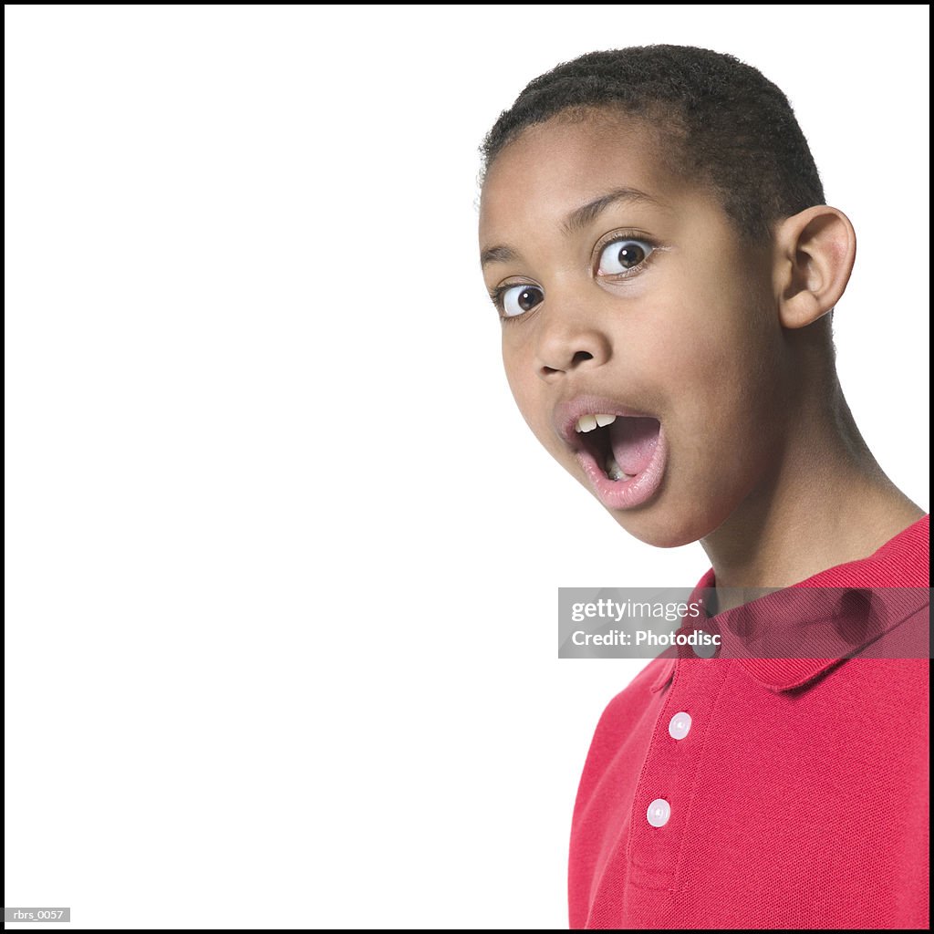 Medium close up shot of a male child in a red shirt as he flashes a surprised look