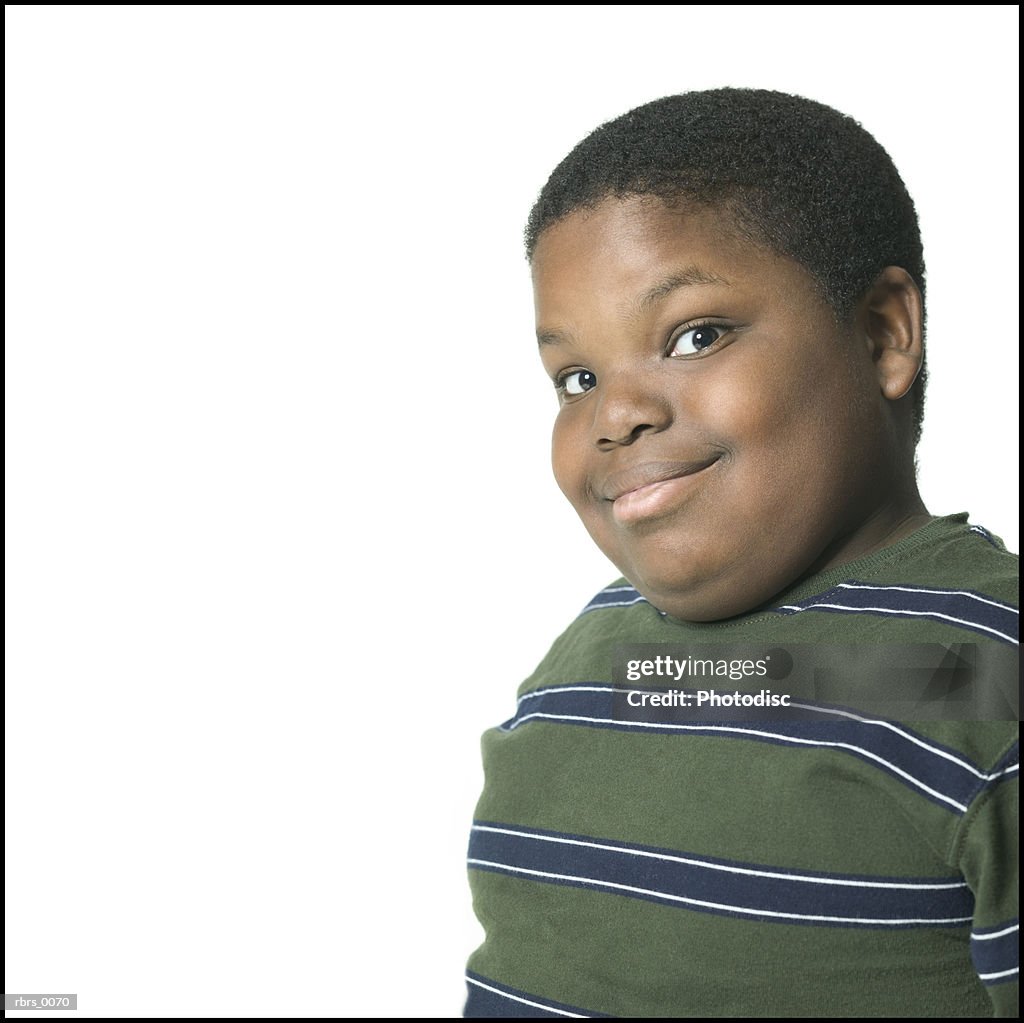 Medium close up of a male child in a green striped shirt as he smirks at the camera