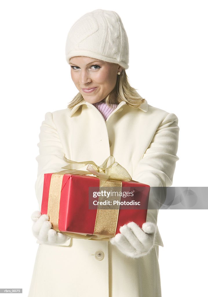 Medium shot of a young adult female in a winter coat as she hold up a christmas gift