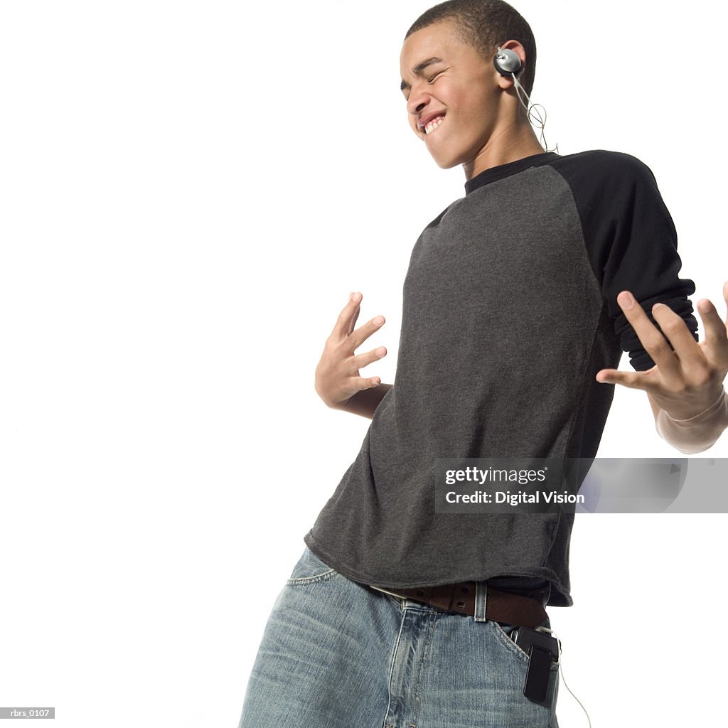 Medium shot of a teenage male as he dances wildly while listening to headphones