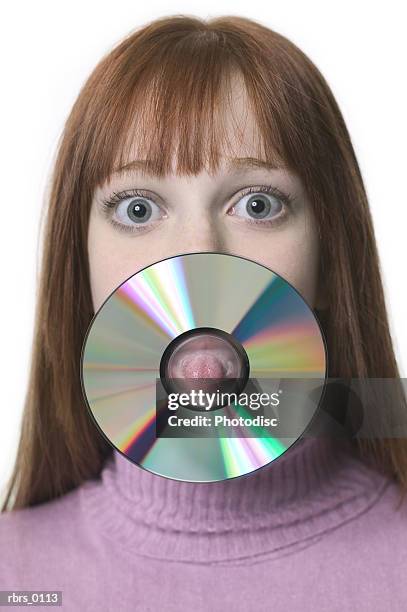 close up shot of a teenage female as she sticks her tongue out through a cd - cd rom stock-fotos und bilder