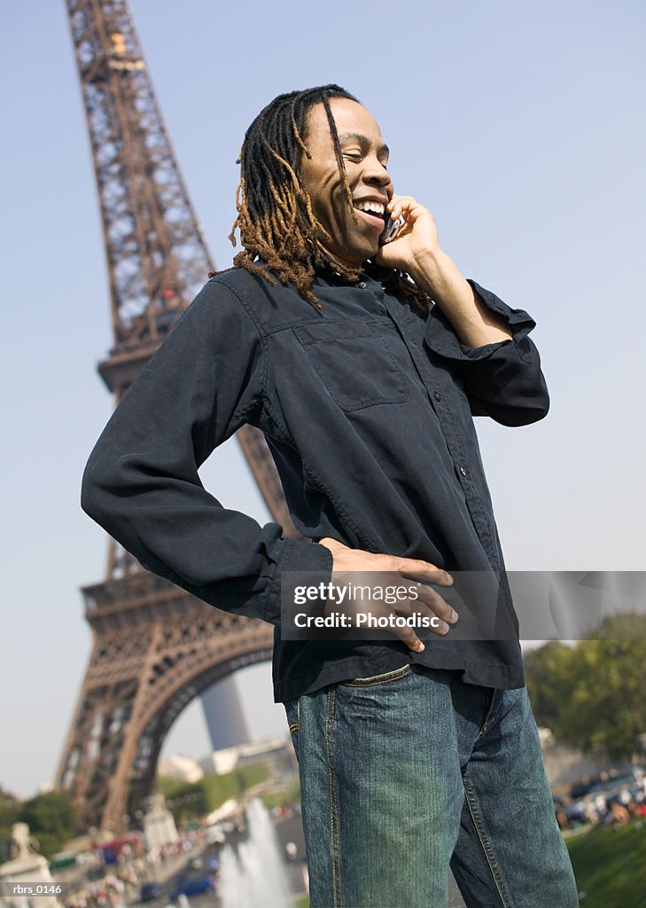 Medium shot of a young adult male as he chats on his cell phone while sightseeing in paris
