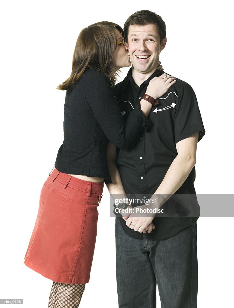 Medium shot of a young adult couple as the woman leans in and kisses the man