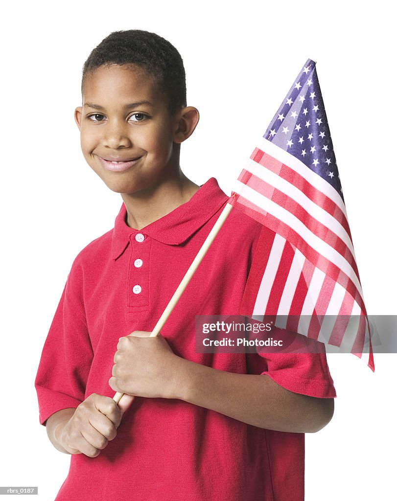 Portrait of a young boy in a red shirt as he holds an american flag and smiles