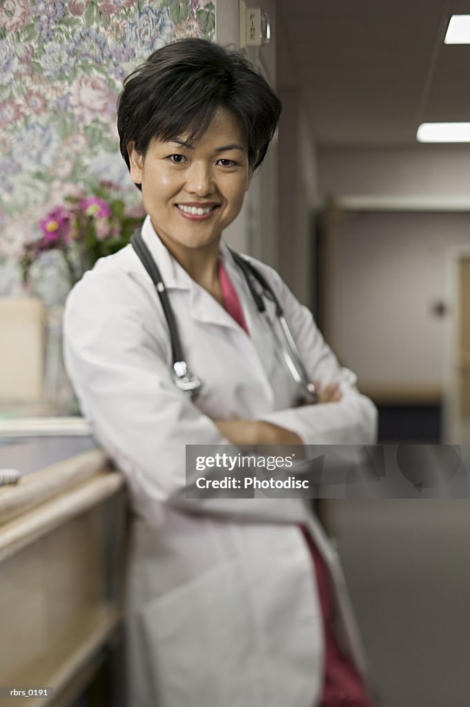 Lifestyle shot of an adult female doctor in a hospital hallway as she folds her arms and smiles