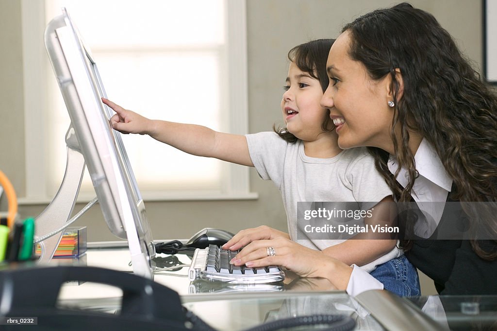 Lifestyle shot of a young adult mother as she and her daughter use her computer