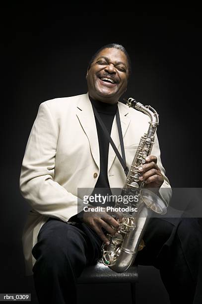 portrait of a man holding a saxophone - bläser stock-fotos und bilder