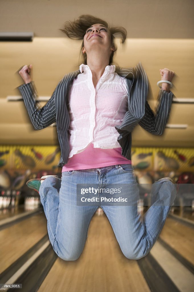 Young woman leaping in a bowling alley