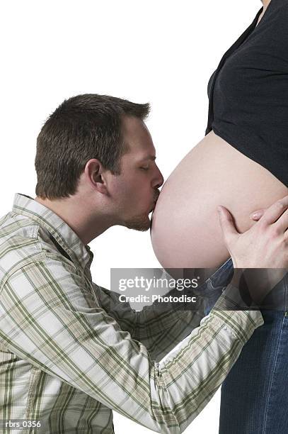 man kissing a pregnant woman's stomach - maternity wear stock pictures, royalty-free photos & images