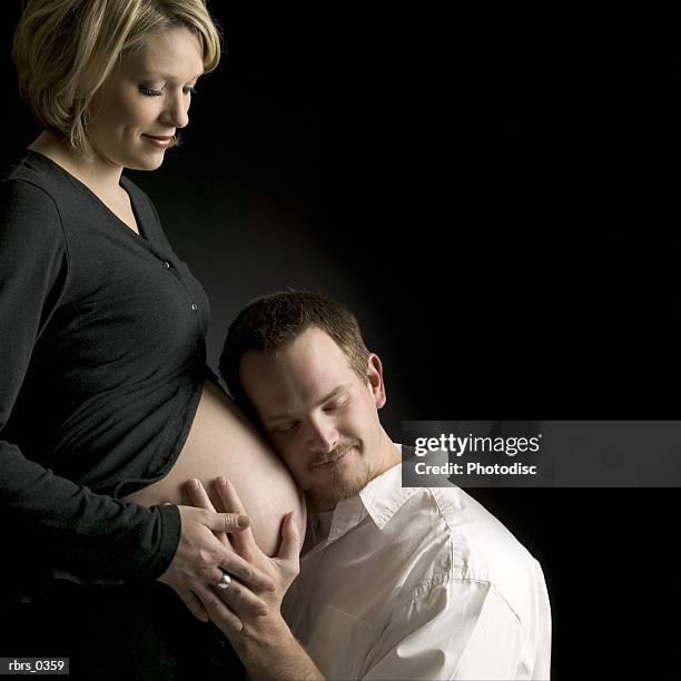 man feeling a pregnant woman's stomach - roupa de grávida imagens e fotografias de stock