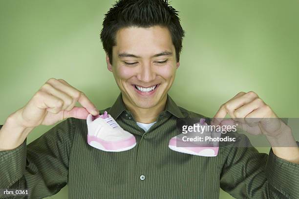 young man holding a shoe - chinese baby shoe stock pictures, royalty-free photos & images