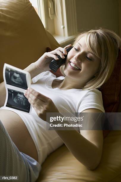 pregnant woman on the phone looking at an ultrasound - maternity wear stock pictures, royalty-free photos & images