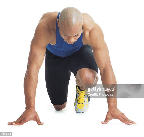 a young bald black male runner wears a blue tank top and leans forward in the starting position - calma antes de la tempestad fotografías e imágenes de stock