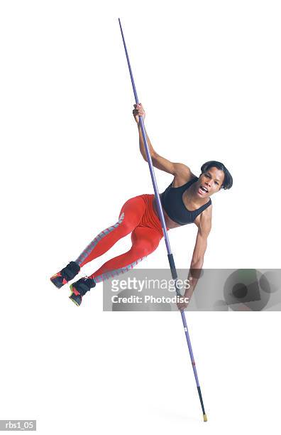 a young black athletic woman in red running pants balances on the tip of her javelin - womens field event stockfoto's en -beelden