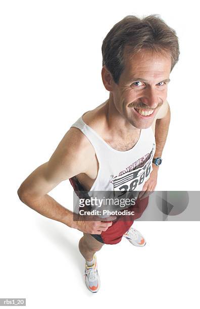 a caucasian man with a mustache is wearing red running shorts and a marathon number as he stands looking up at the camera - la marathon - fotografias e filmes do acervo