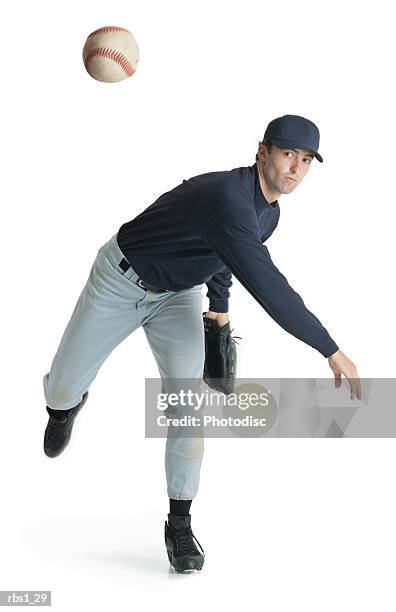 a caucasian man wearing a blue and white baseball uniform is leaning forward after throwing a ball - baseball ball stock-fotos und bilder