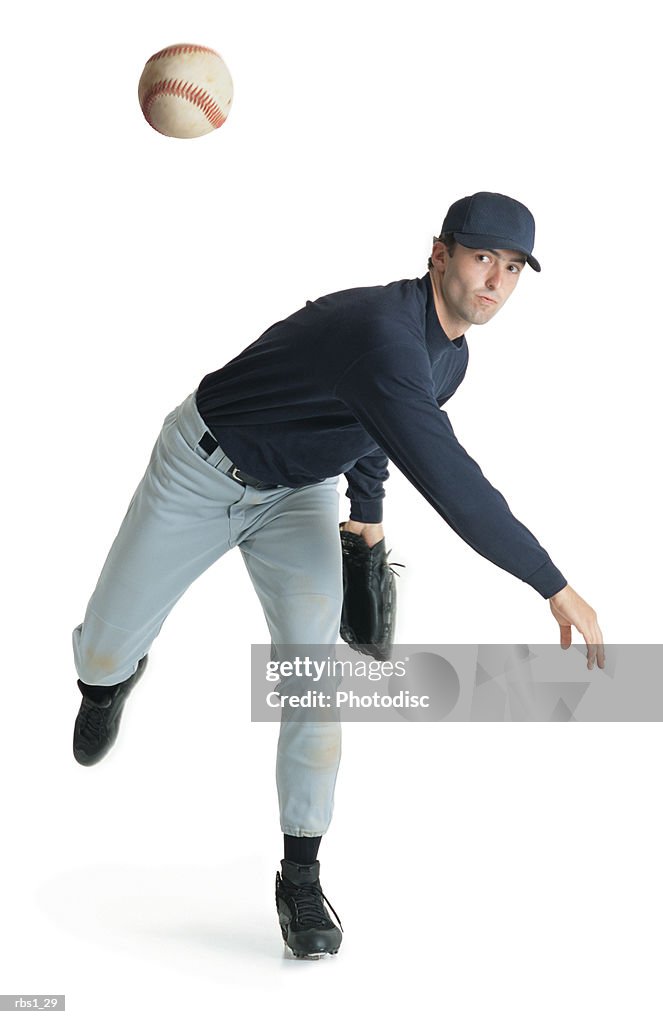 A caucasian man wearing a blue and white baseball uniform is leaning forward after throwing a ball