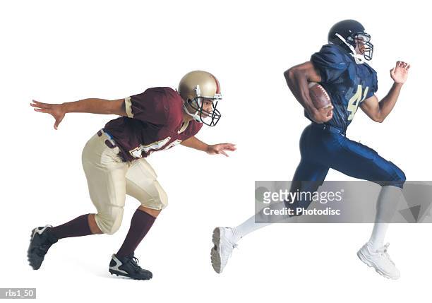 two african american american football players from opposing teams are running as the one in front holds the football and the other tries to catch him - tackling stock pictures, royalty-free photos & images