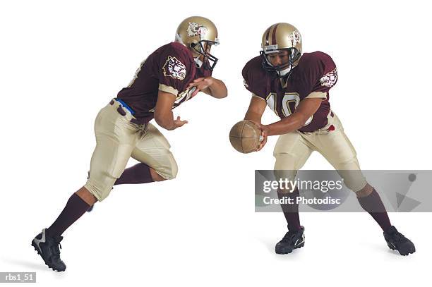 two african american football players wearing red and white uniforms are running towards each other as one prepares to pass the ball to the other - quarterback isolated stock pictures, royalty-free photos & images