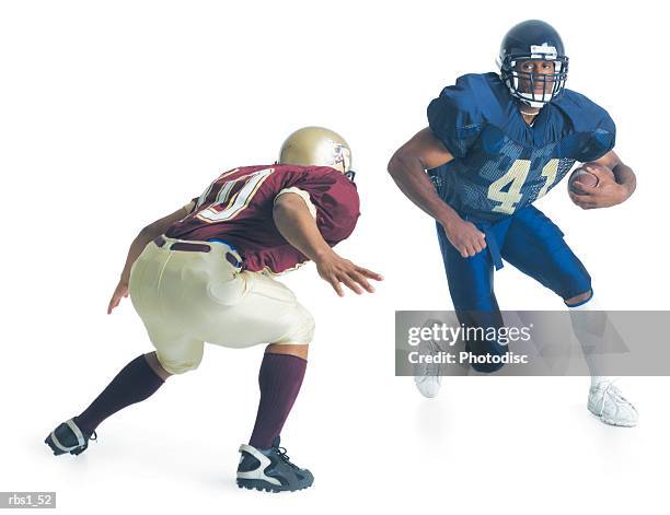 two football players from opposing teams are running towards each other as one holds the football and the other crouches forward to stop him - tackle stock pictures, royalty-free photos & images