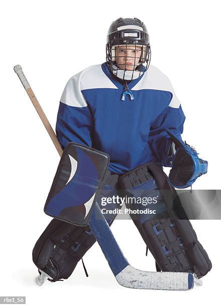 a little caucasian boy dressed in a hockey uniform stands with legs apart scowling through his goalie mask - ice hockey player stock pictures, royalty-free photos & images