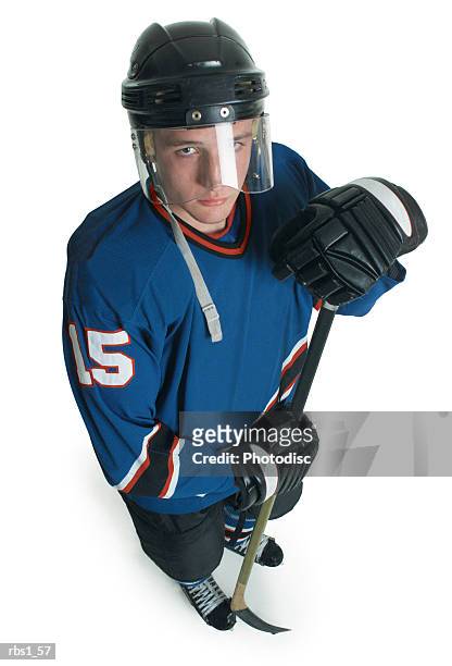 a young caucasian male hockey player in a blue jersey and face shield stands and confidently looks up at the camera - ijshockeytenue stockfoto's en -beelden