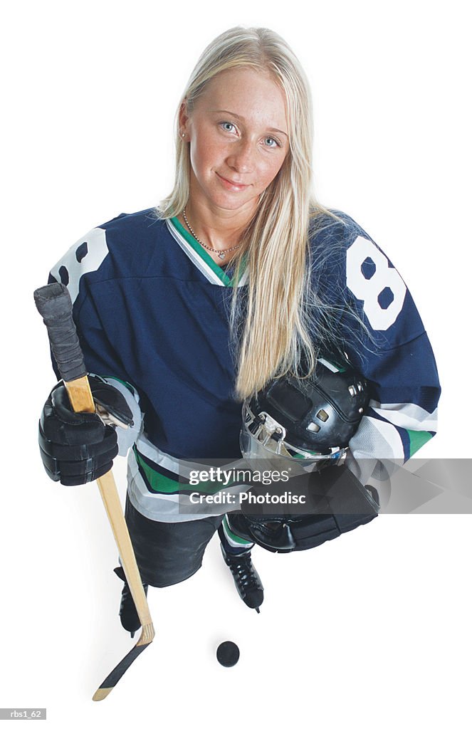 An attractive young caucasian female hockey player with long blonde hair and wearing a blue jersey smiles as she looks up at the camera