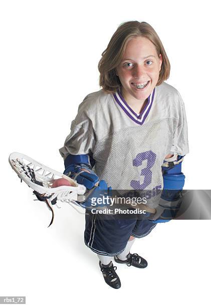 a teenage caucasian female in a white jersey holds her lacrosse racket and smiles as she looks up into the camera - lacrosse stock pictures, royalty-free photos & images