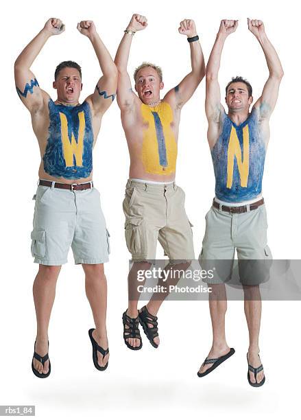 three shirtless caucasian male super fans with the letters w i n painted on their chests jump in the air in celebration - touchdown letters stock pictures, royalty-free photos & images