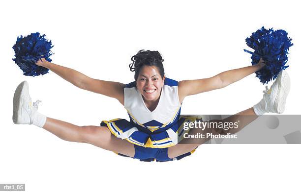 an ethnic teenage female cheerleader jumps high in the air and does the splits - cheerleader white background stock pictures, royalty-free photos & images