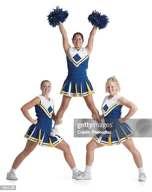 three teenage caucasian female cheerleaders in blue uniforms cheer as they form a small pyramid - ragazza pon pon foto e immagini stock
