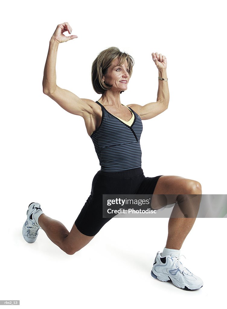 An adult caucasian female in a gray shirt and black shorts as she works out and does areobics