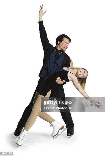 caucasian female leans back on the arm of caucasian male ice skating partner with outstretched arms - figure skating couple stock pictures, royalty-free photos & images